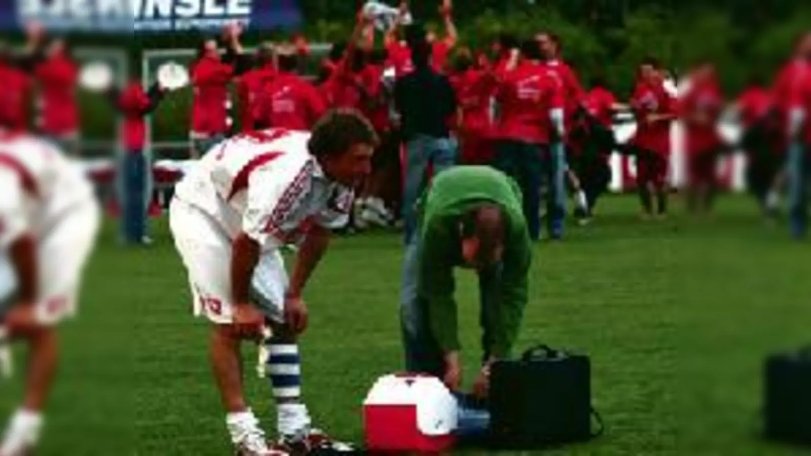 Wunden lecken nach dem traurigen Finale: Unterföhrings Abwehrchef Jürgen von Kolzenberg lässt sich behandeln, während hinter ihm der FC Memmingen II wild den Aufstieg feiert.	  (Foto: ba)