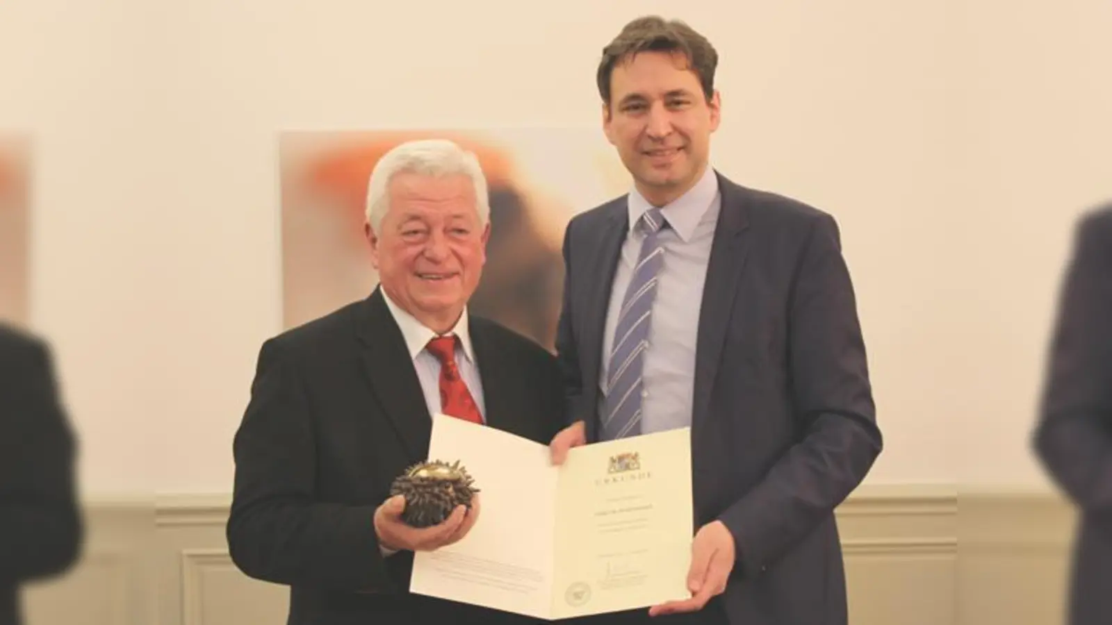 Dr. Peter Riedner erhält den Staatspreis aus den Händen von Staatssekretät Georg Eisenreich. Es ist die Anerkennung für jahrzehntelange Arbeit, mit der Riedner jungen Menschen den Weg zu ihrem Platz in der Gesellschaft gezeigt hat.	 (Foto: © StMBW)