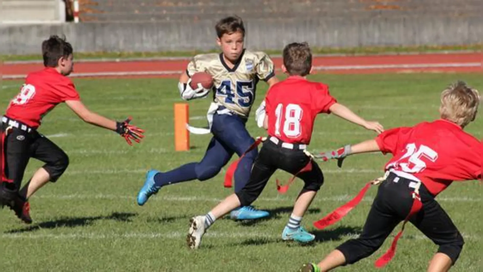 Johann Wittenburg (45) gibt alles, um den heranstürmenden Razorbacks Verteidigern (rote Trikots) mit dem Ball zu entkommen, die bereits die Hände nach den weißen Flags strecken, um Wittenburg durch Ziehen der Flags zu stoppen.	 (Foto: M. Kröner)