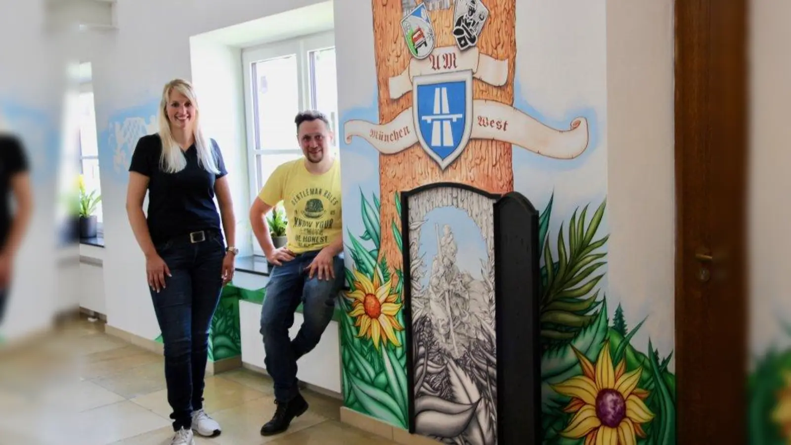 Tradition und Moderne zum 80-jährigen Jubiläum: Dienststellenleiterin Annette Schöpf und der Pasinger Maler Martin Blumöhr vor dem gemalten Stammbahn in der Autobahnmeisterei München-West. (Foto: us)