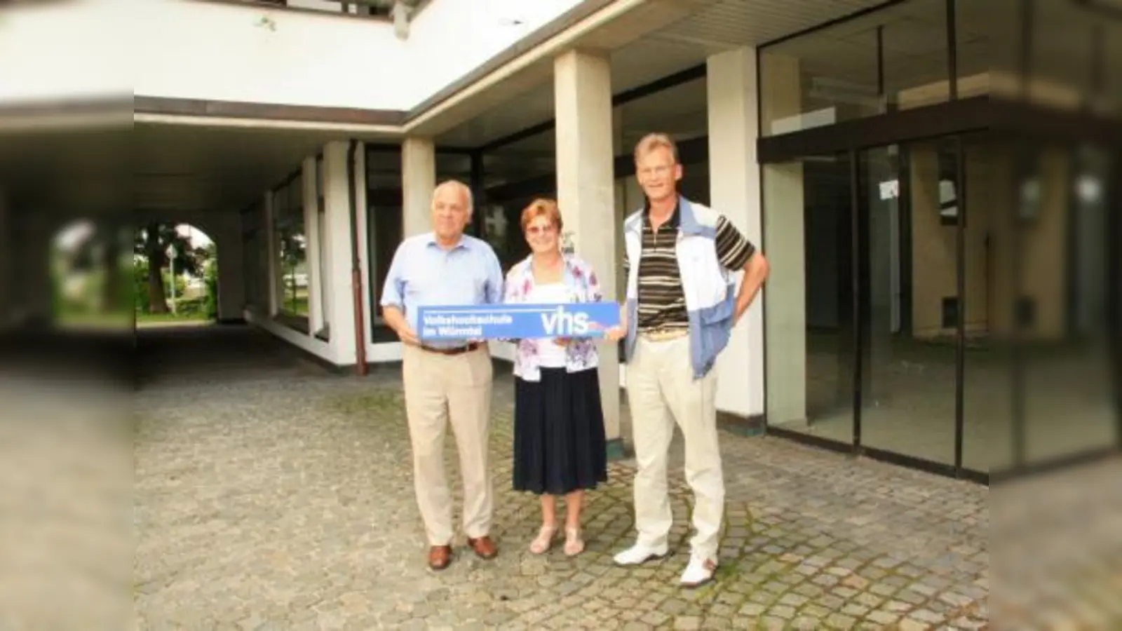 Die VHS Würmtal hat am Planegger Marktplatz endlich ein eigenes Zuhause. Im kommenden Schuljahr muss sich die Schule allerdings noch provisorisch im Übergangsheim zurechtfinden. Jochen Schwerdtner, Annemarie Detsch und Kurt Landwehrmann (v.l.) präsentieren schon einmal das Schild am neuen Eingang. (Foto: US)