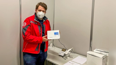 Florian Weber zeigt eines der neuen molekulardiagnostischen Testsysteme für die Testauswertung. (Foto: Johanniter/Jason Podt)