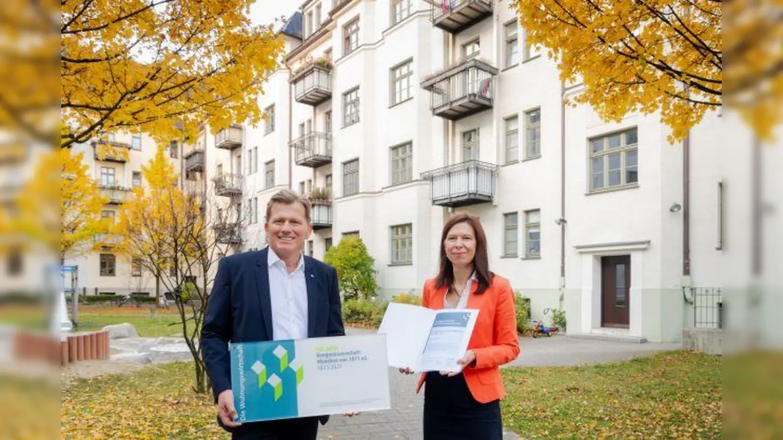 Verbandsdirektor Hans Maier übergibt ein Jubiläumsschild der Wohnungswirtschaft an Vorstand Sandra Marko. (Foto: VdWBayern / Andreas Heddergott)