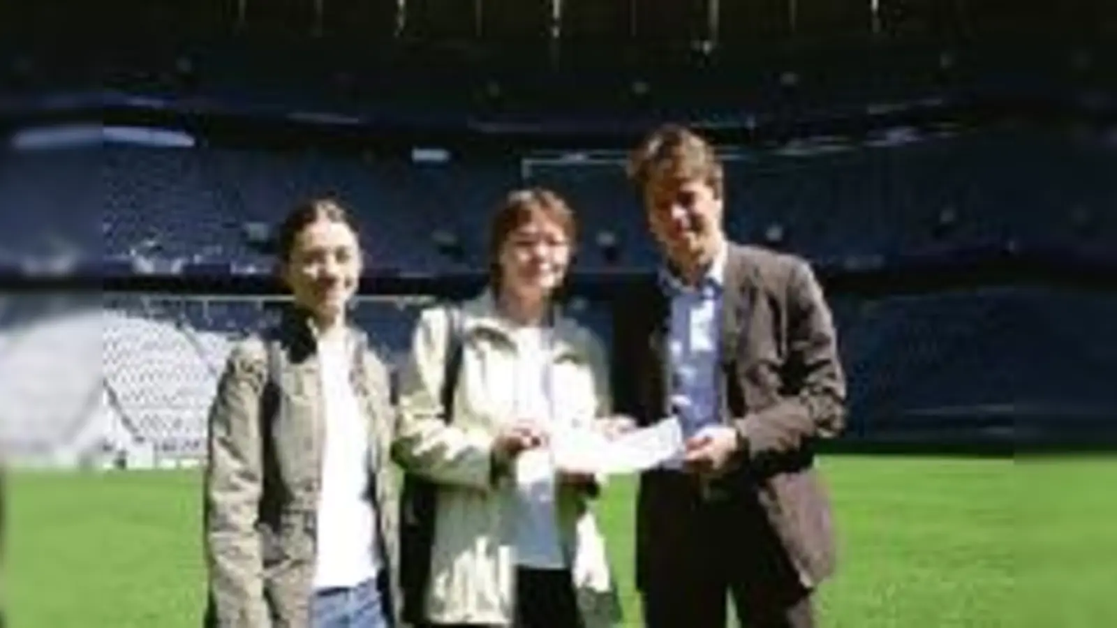 Ilona Kraus und Tochter Ramona nehmen die beiden Tickets von Alexander Pieper (Geschäftsleitung Marketing bei Arena One) im Mittelkreis des Spielfeldes in der Allianz Arena entgegen.	  (Foto: cr)