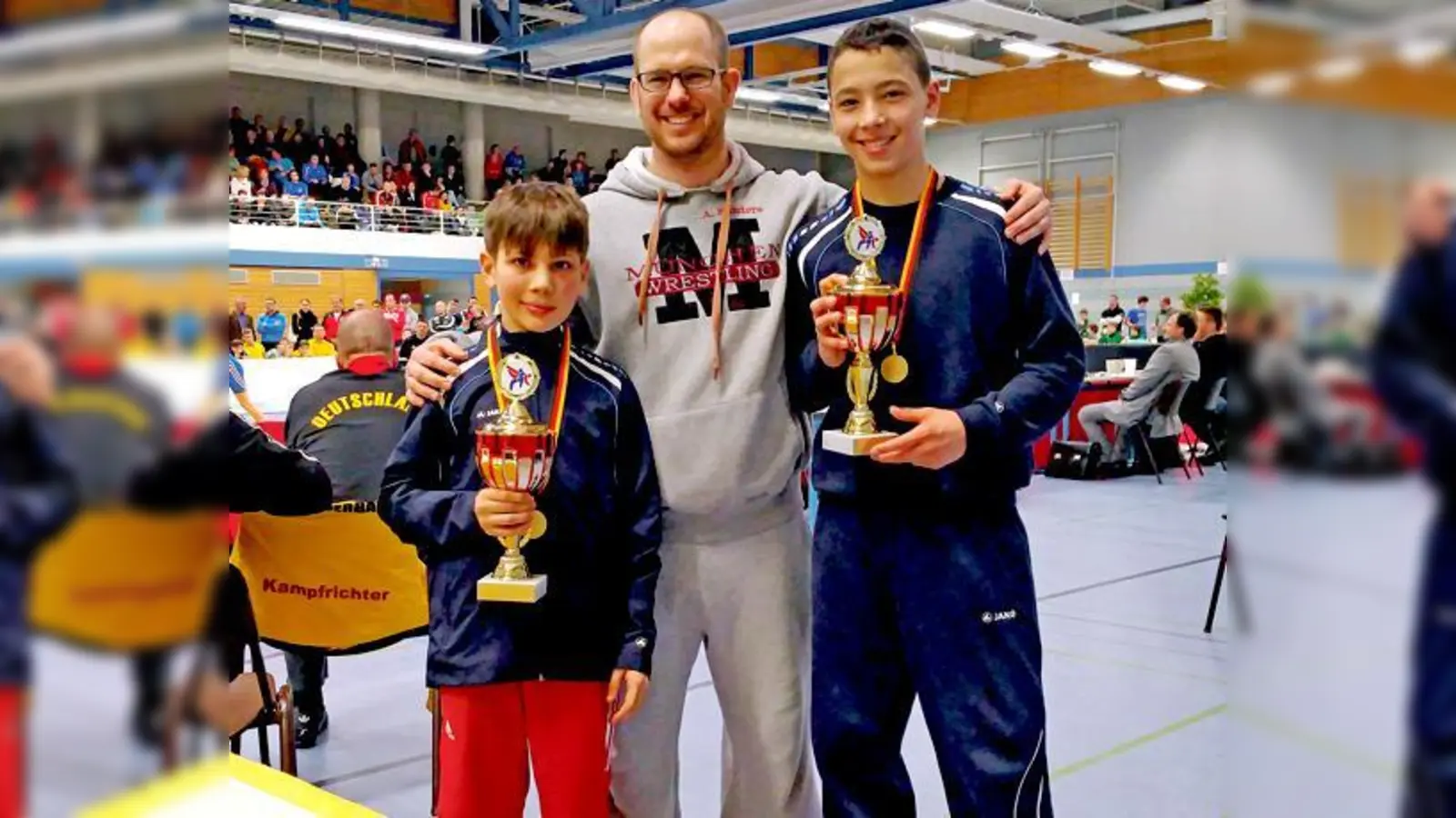 Stolze deutsche B-Jugend-Meister: Die Ringertalente David Brand (links) und Mohammad Schwäbisch (rechts) mit ihrem Trainer Aaron Sanders.	 (Foto: Verein)