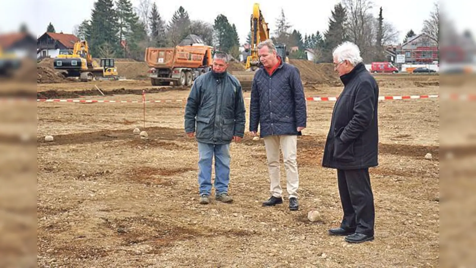 Adolf Dransfeld, Bürgermeister Jan Neusiedl und Wolfgang Kuny (von links) am Fundort. Am Boden sieht man einen Teil der Gebäudespuren, im Hintergrund weitere Baggerarbeiten auf dem Gelände.	 	 (Foto: Gemeinde Grünwald)