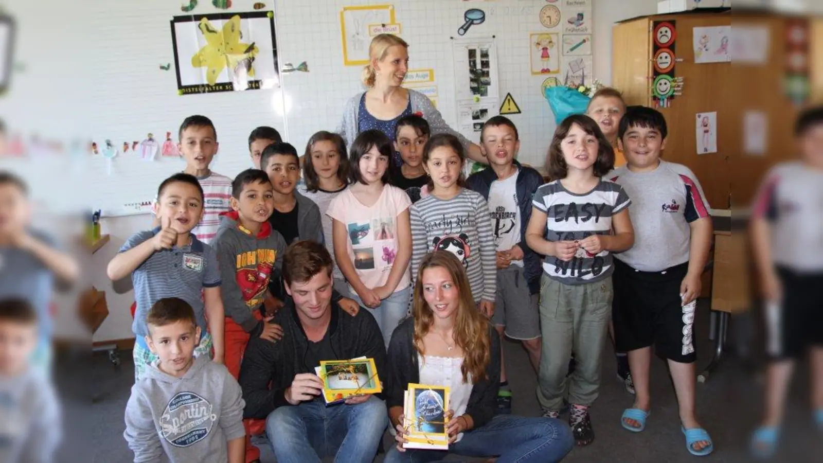 „Bei uns ist Integration kein Fremdwort.” Die Übergangsklasse in der Grundschule an der Bäckerstraße hat 15 Kinder im Alter von sieben bis zehn Jahren aus zehn Ländern. Hinten im Bild Lehrerin Mirjam Huber, vorn die Praktikanten Hannah und Leo (Foto: us)