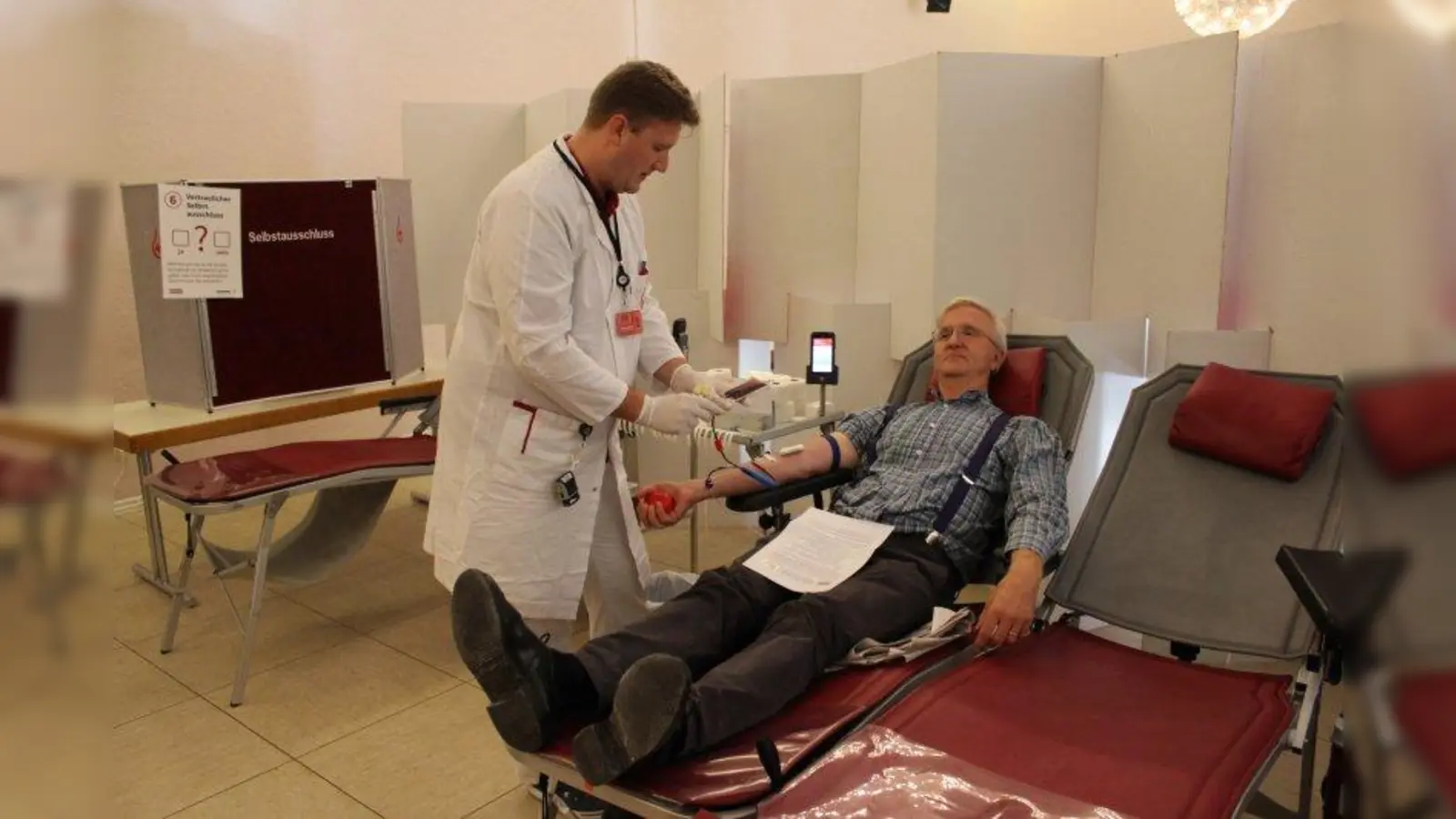 Marko Hammer (links), Mitarbeiter des Blutespendedienstes des Bayerischen Roten Kreuzes (BRK), bereitet Alfred Maier, Vorstand des Kolping-Bildungswerkes München und Oberbayern, auf seine Blutspende vor. (Foto: sb)