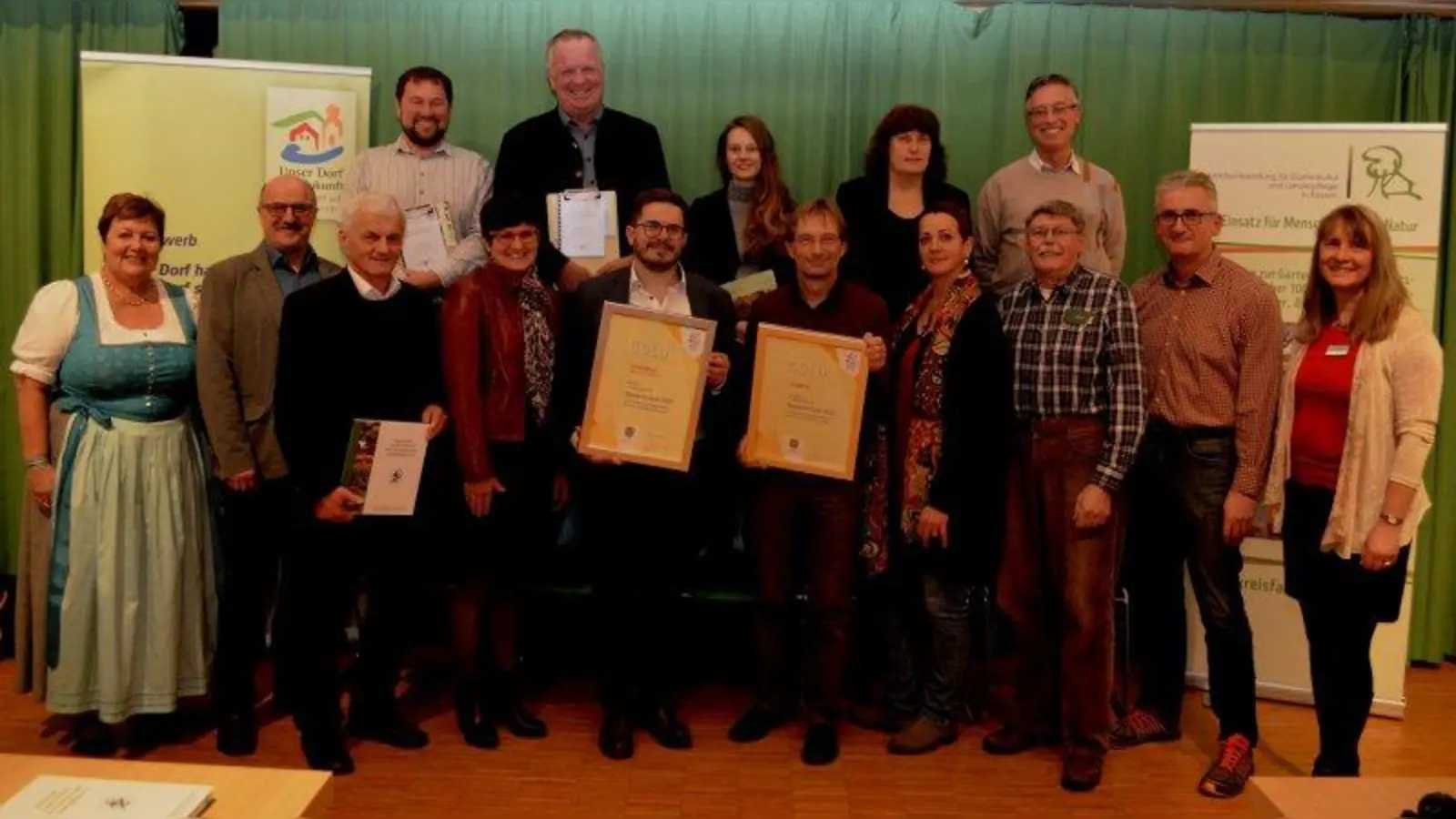 Goldmedaillen für die Gemeinden Huglfing und Schönberg mit ihren Bürgermeistern Bernhard Kamhuber, Fünfter von rechts) und Markus Bader (Fünfter von links) aus der Hand von Andrea Jochner-Weiß (links) und Heike Grosser (rechts). Hinten steht die Jury. (Foto: mka)