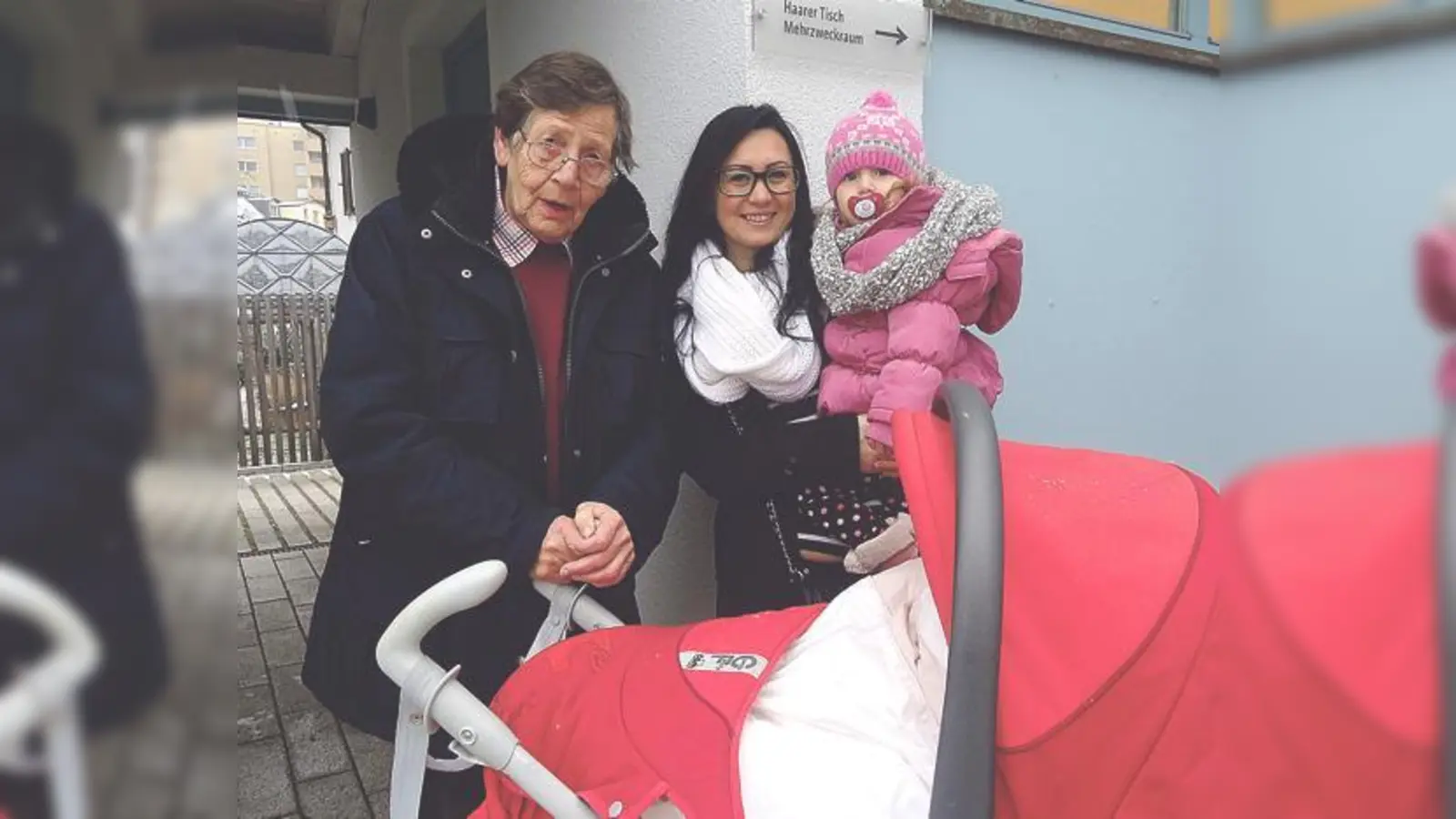 Traudl Vater vom Haarer Tisch nimmt den Kinderwagen von Ribana Nardi mit ihrer Tochter Soraya entgegen.	 (Foto: Gemeinde Haar)