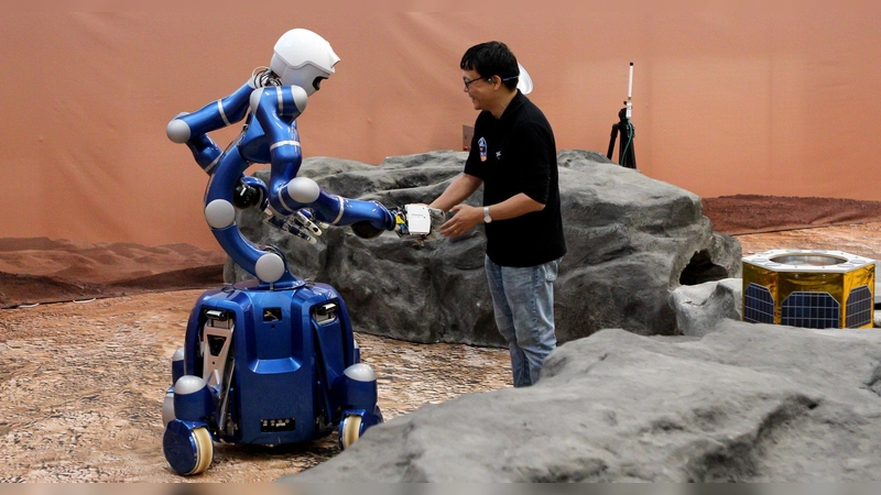 DLR-Wissenschaftler Neal Lii und NASA-Astronaut Jonny Kim schütteln sich per Kraftrückkopplung durch den Roboter die Hände. (Foto: Erlend Hellerslien)