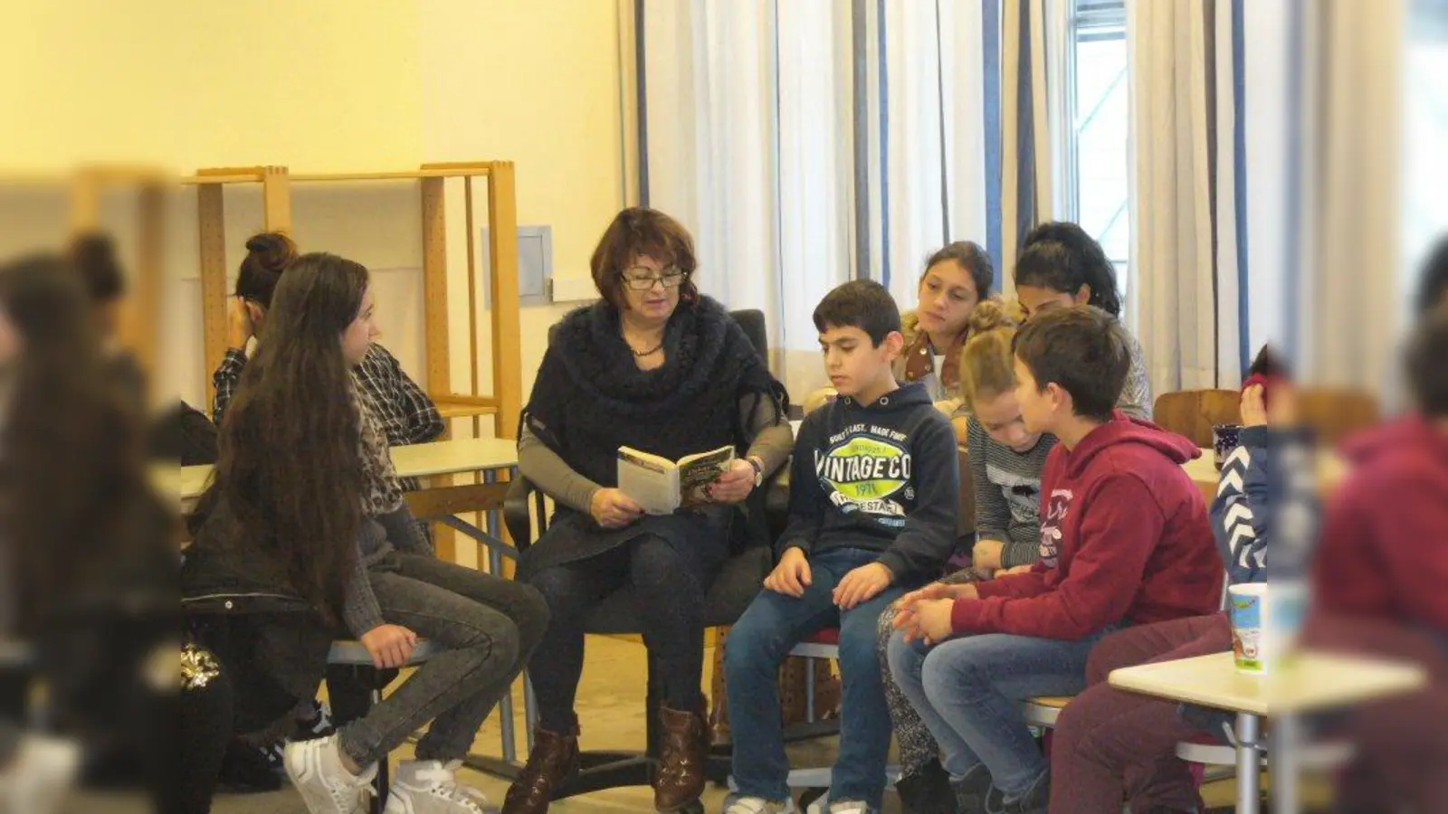 Ingrid Neff beim Vorlesen vor Fünft- und Sechstklässler. Zur Vorlesezeit werden die Klassenverbände zumeist aufgelöst, damit alle Kinder zuhören können. (Foto: Förderverein Peslmüllerschule)