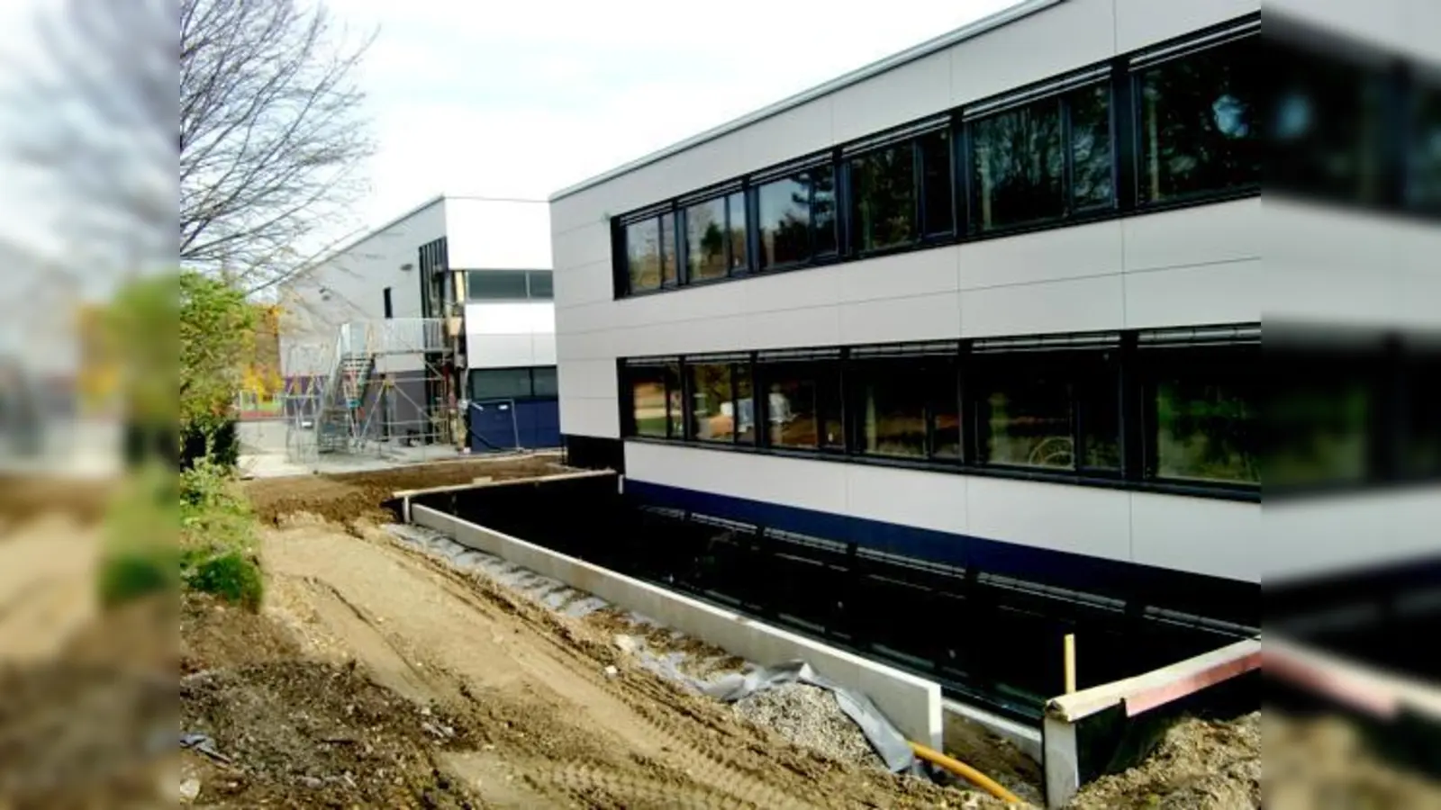 Die sanierte Turnhalle (hinten) des Gymnasiums ist jetzt fertig, der Anbau (vorne) kann um Ostern kommenden Jahres bezogen werden.	 (Foto: hgb)