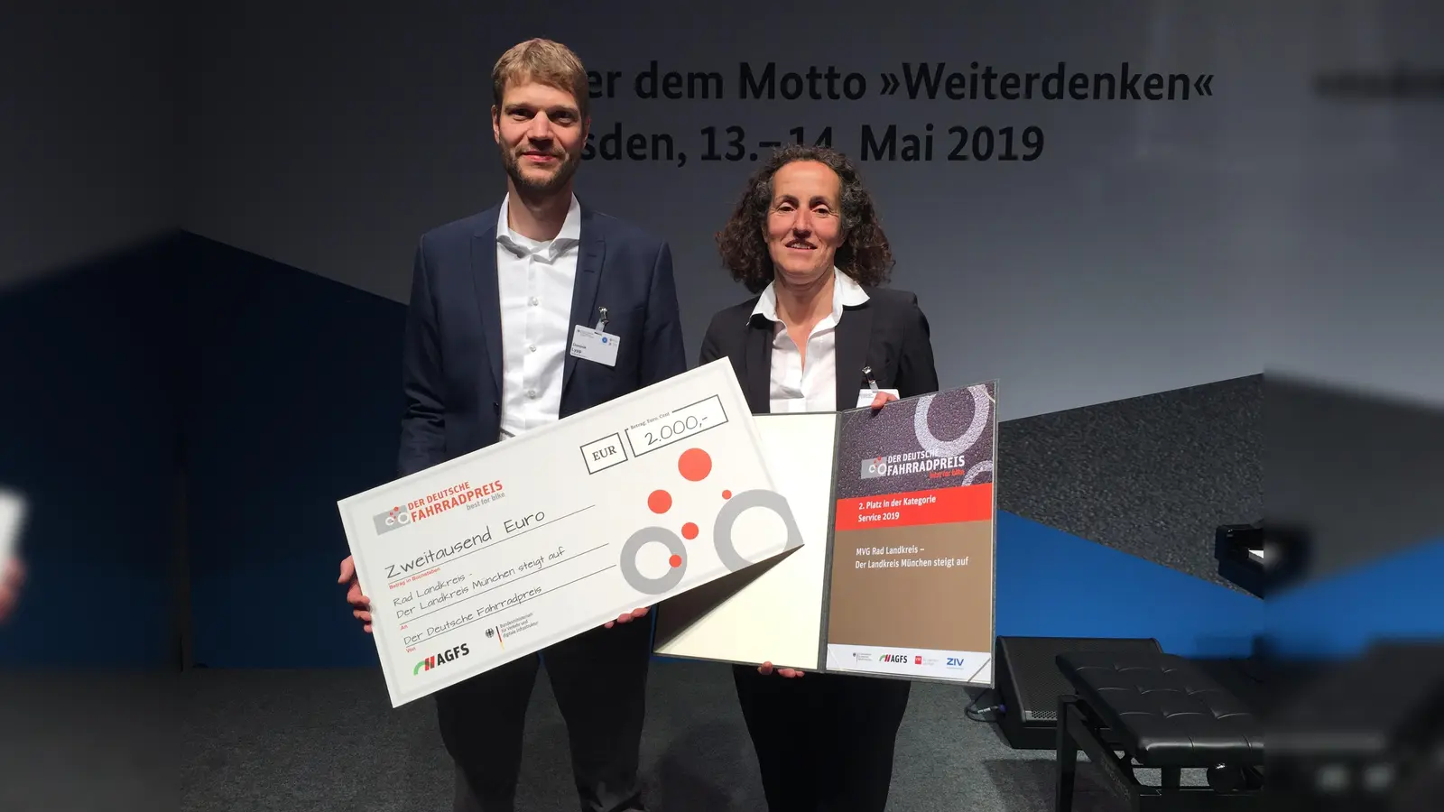 2.000 Euro erhält der Landkreis München für den zweiten Platz beim Deutschen Fahrradpreis. Dominik Lypp, Leiter des Projekts im Landratsamt, und Sonja Rube, Projektleiterin für die MVG, nahmen Scheck und Urkunde entgegen. (Foto: Landratsamt München)