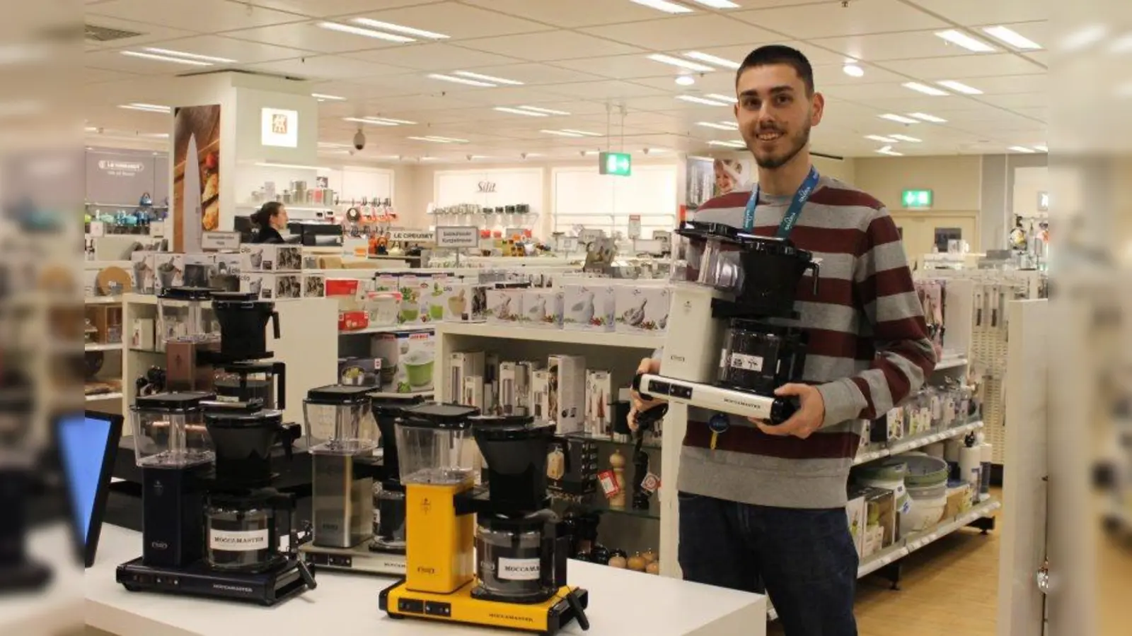 Eren Cesur, Auszubildender in der Galeria Kaufhof am Rotkreuzplatz, präsentiert die „Moccamaster”-Kaffeemaschinen, die es in 21 verschiedenen Farben gibt. (Foto: sb)
