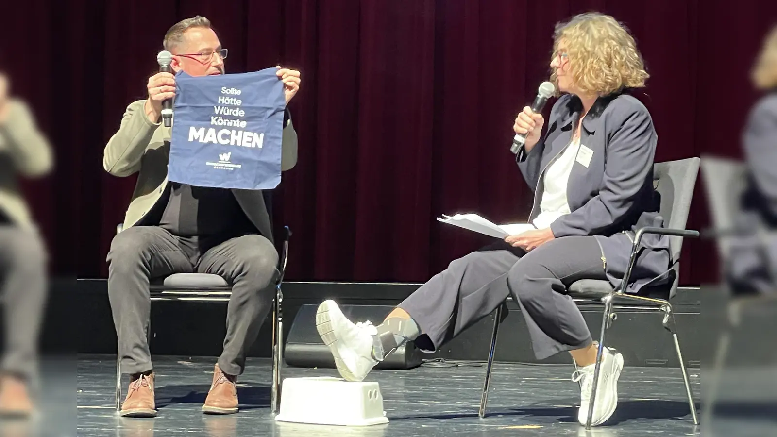 „Sollte, hätte, würde, könnte - Machen”, Jürgen Andre zeigt Katrin Schmidt den neuen Stoffbeutel des Wirtschaftsverbands. (Foto: pst)