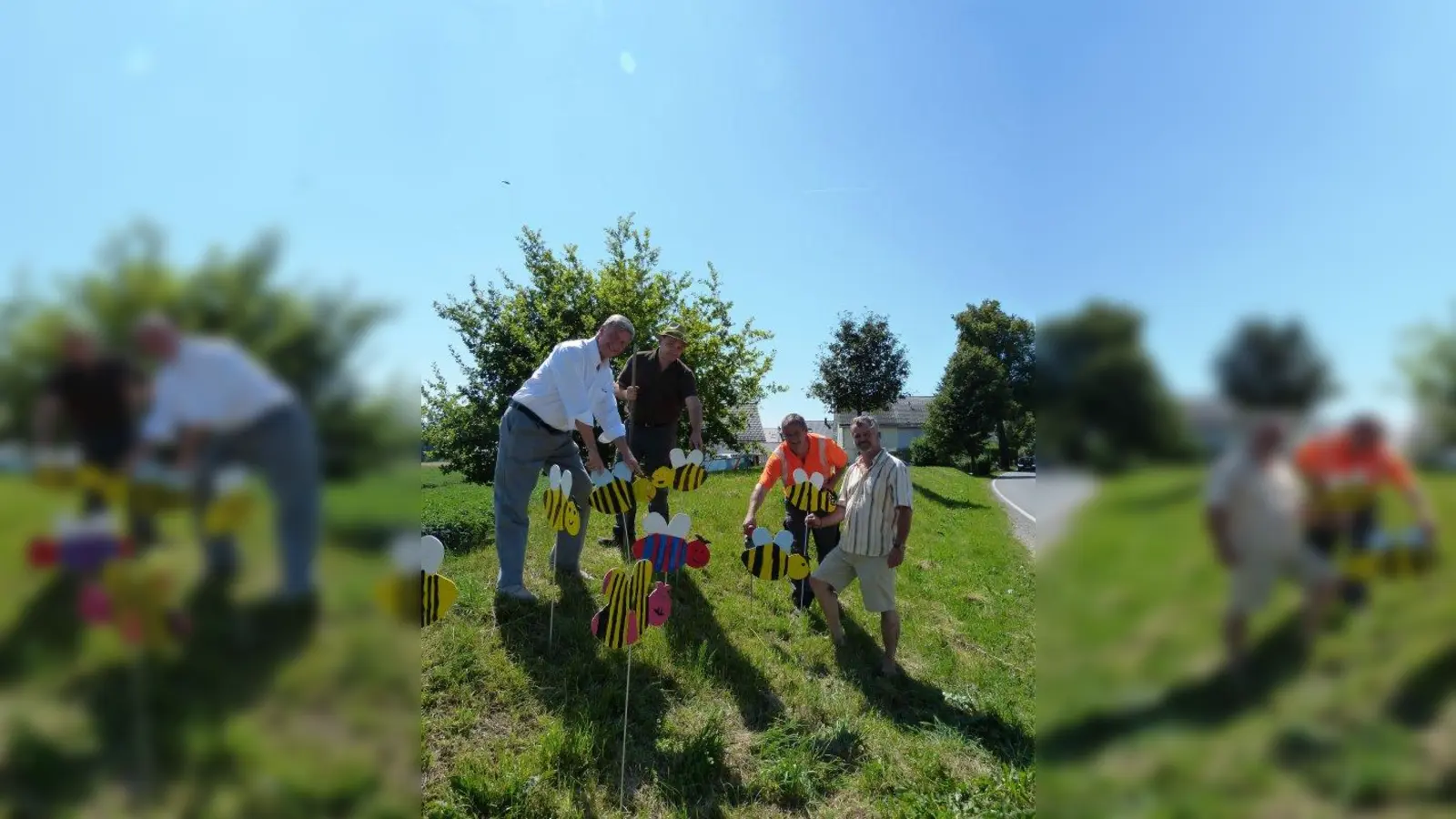 Der Bauhof hat das bunte Bienenvolk an schönen Plätzen in Alling verteilt, so wie hier am Ortseingang von Hoflach kommend. Ideengeber Michael Speidel (rechts) und Bürgermeister Frederik Röder (links) legten mit Hand an. (Foto: Gemeinde Alling)