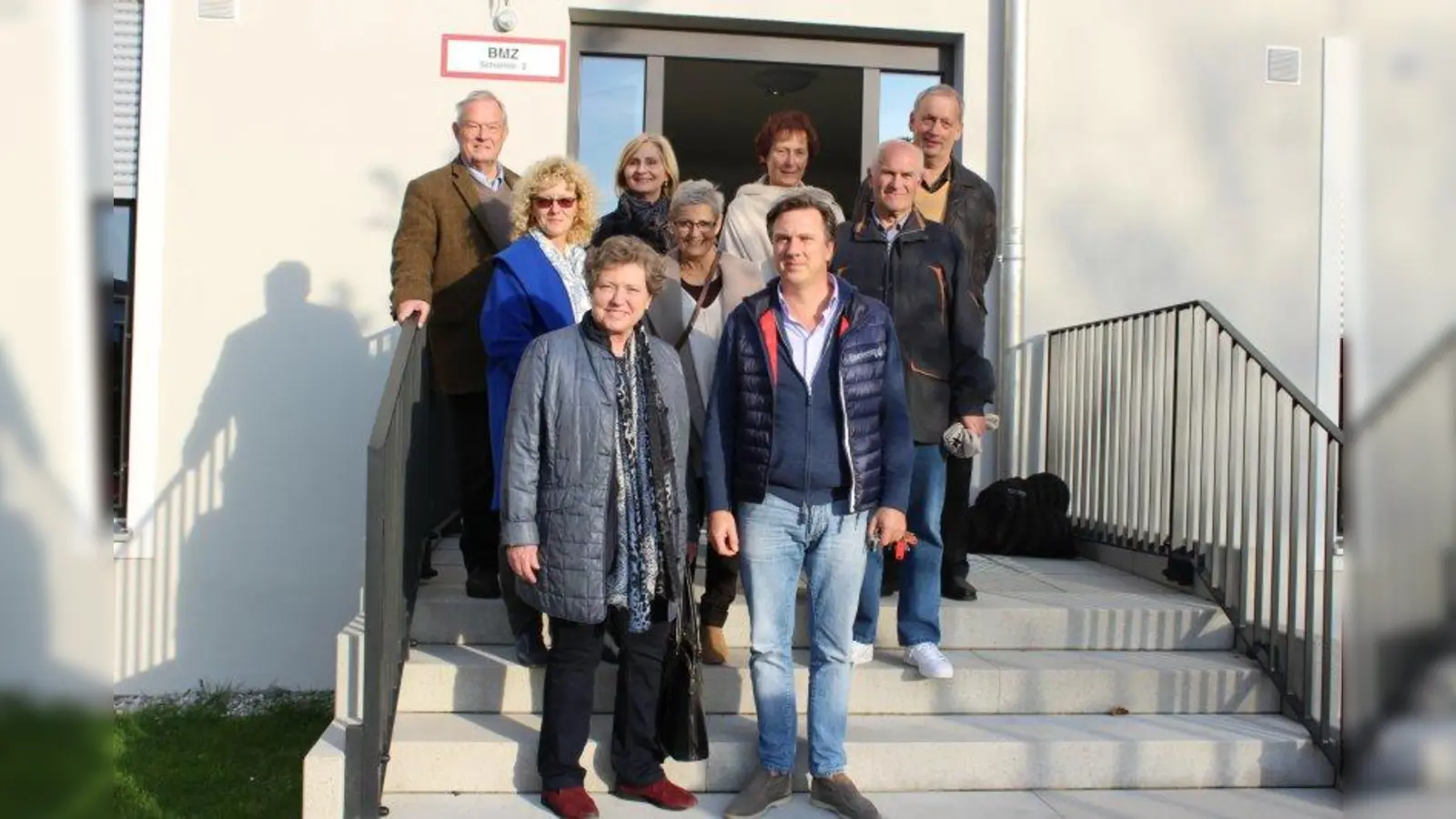 Heike Kainz (vorne l.), Vorsitzende des Bezirksausschusses Allach-Untermenzing, zusammen mit Lars Hanninger (vorne r.) von der Betreiberfirma der Wohnungslosenunterkunft in der Schöllstraße und ihren BA-Kollegen Gabriele Hartdegen, Christiane Schenk, Johann Wagner (mittlere Reihe v.l.), Henning Clewing, Ingrid Haussmann sowie Christine und Falk Lamkewitz (hintere Reihe v.l.). (Foto: sb)