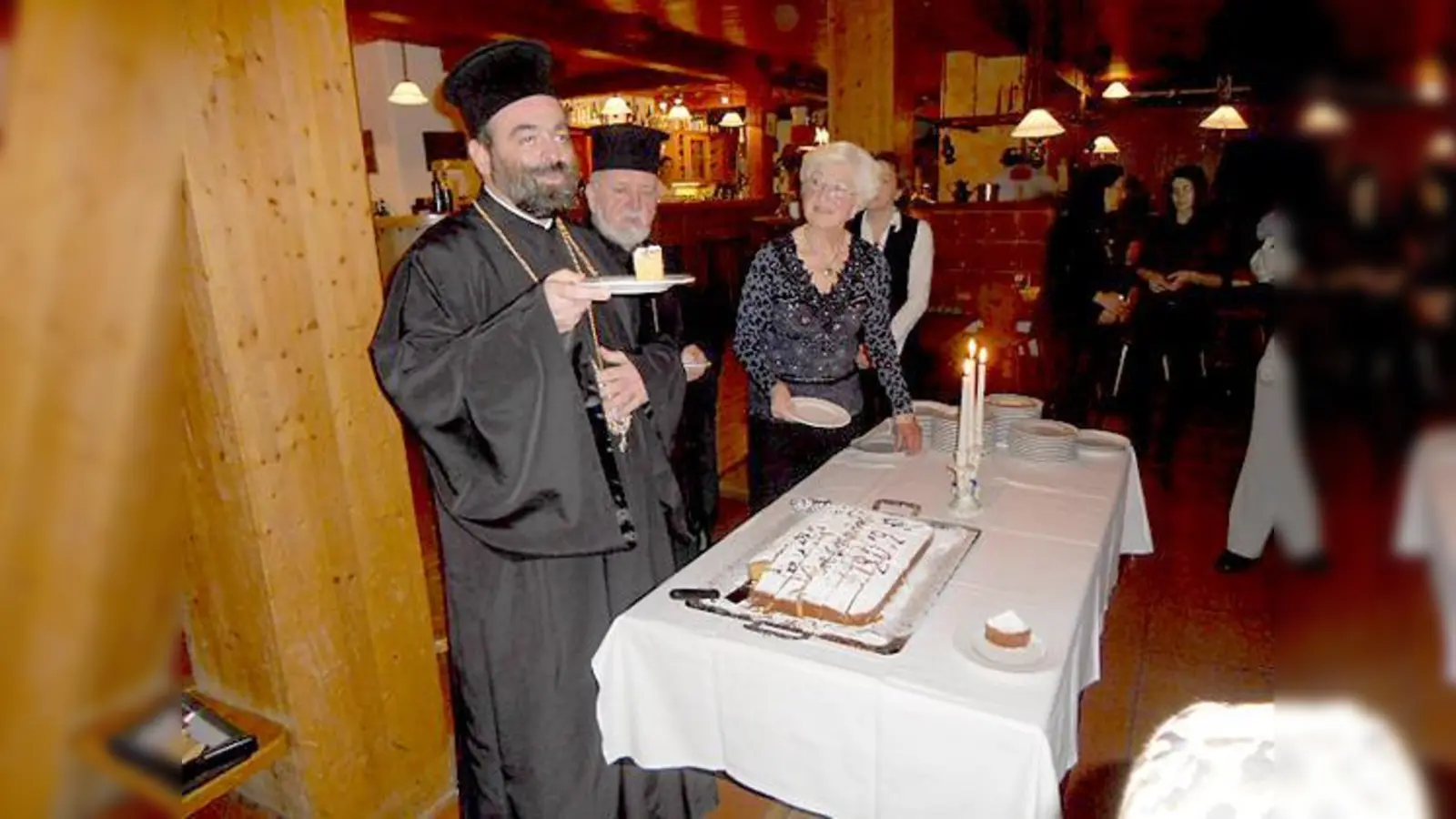 Fromm und fröhlich: Bischof Bartholomäos von Ariaszos präsentiert das erste Stück Neujahrskuchen. Weiterhin zu sehen Erzpriester Apostolos Malamoussis (Mitte) und Thilde Schmitz. 	 (Foto: privat)