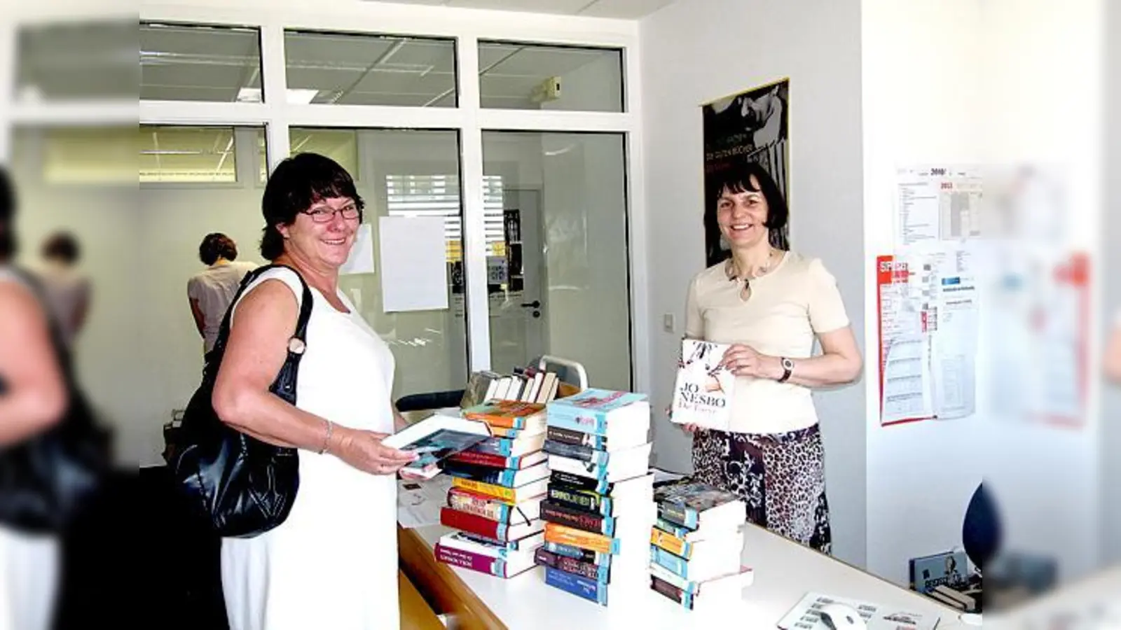 Daniela Heim vom Bücherei-Team (r.) rät den Nutzern sich mit reichlich Lesestoff bis zur Wiedereröffnung im Oktober einzudecken.	 (Foto: Woschée)
