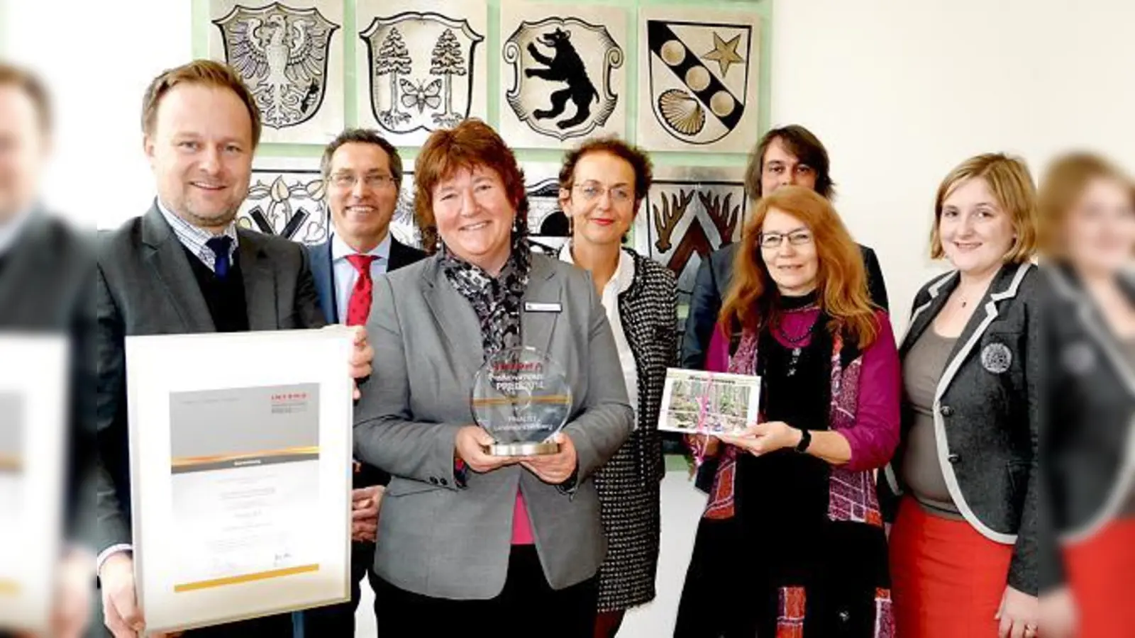 Robert Niedergesäß mit der Urkunde zum Innovationspreis 2014, Brigitte Keller mit dem Preis und Susanne Müller-Hertling mit der Fotodokumentation, daneben: Stefanie Geisler. (Hinten v. li.): Christian Salberg, Carola Schreiner und Oliver Couvigny.  (F: LRA)