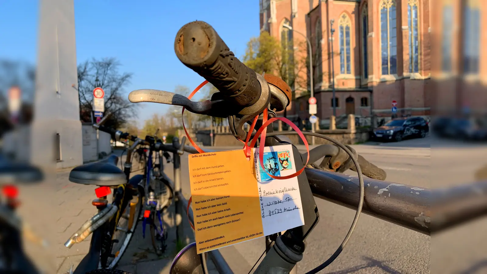 Das Gedicht „Selfie mit Mundschutz“ von Thomas Glatz hängt an einem verwaisten Radl gegenüber der Heilig-Kreuz-Kirche in Giesing. (Foto: Poesieboten)