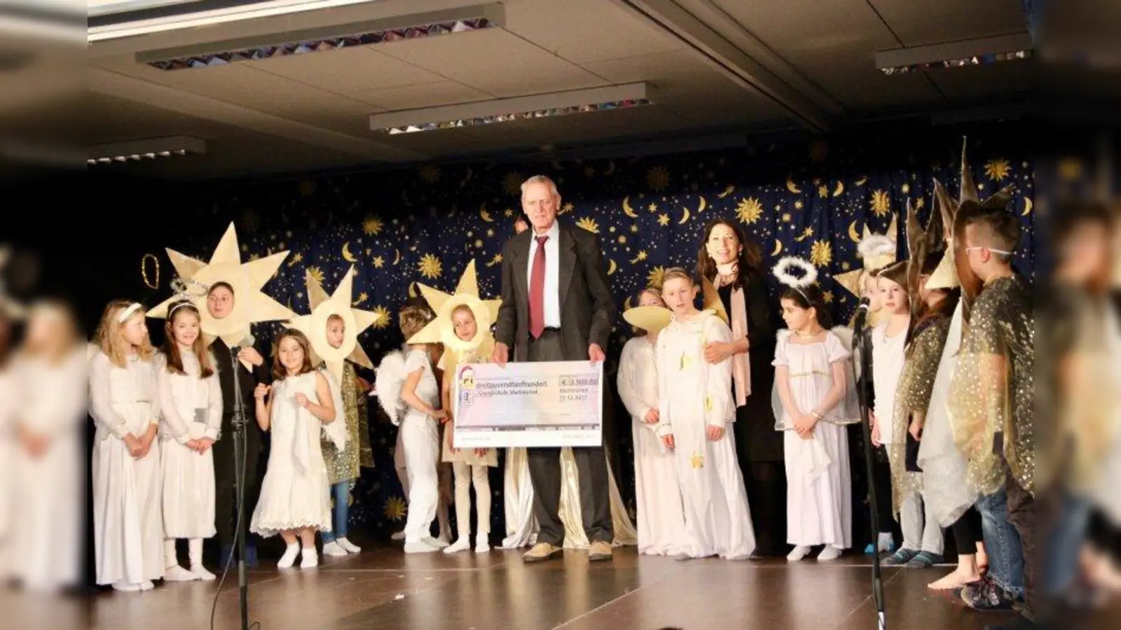 Großzügige Nachbarn: die Martinsrieder Dr. Schenk GmbH spendete der Schulfamilie 3.500 Euro, die nun in die Anschaffung von iPads fließen. Als Vertreter der Firma überreichte Hans Örley den symbolischen Scheck an Schulleiterin Margit Baran-Lander und die Theaterkinder. (Foto: us)