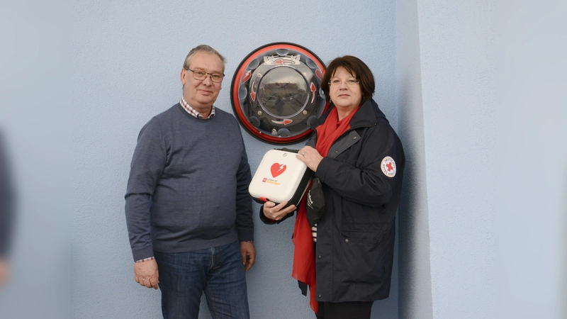 BRK Kreisgeschäftsführerin Elisabeth Seibl-Kinzlmaier installierte zusammen mit Friedrich Peschel einen neuen AED (Automatischer Externer Defibrillator). (Foto: BRK Ebersberg)