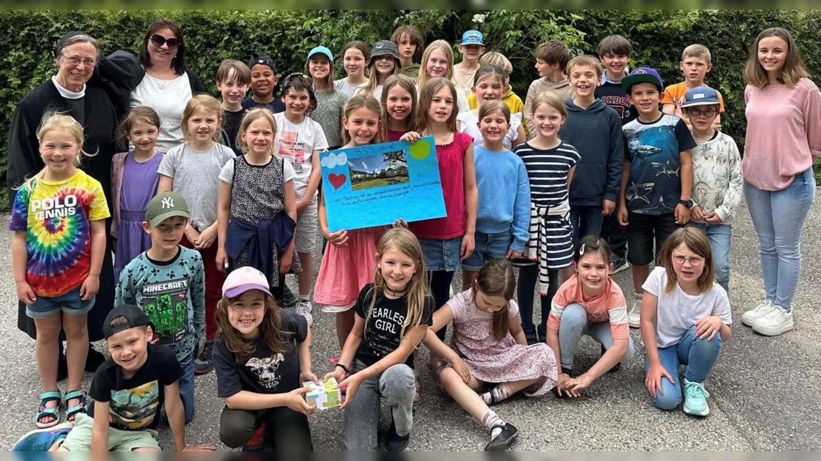 Die „Krambambulinis“ übergeben eine Spardose und ein selbstgestaltetes Plakat an Schwester Angela vom Kinderhospiz Pfaffenwinkel im Kloster Polling. (Foto: Kinderhort)