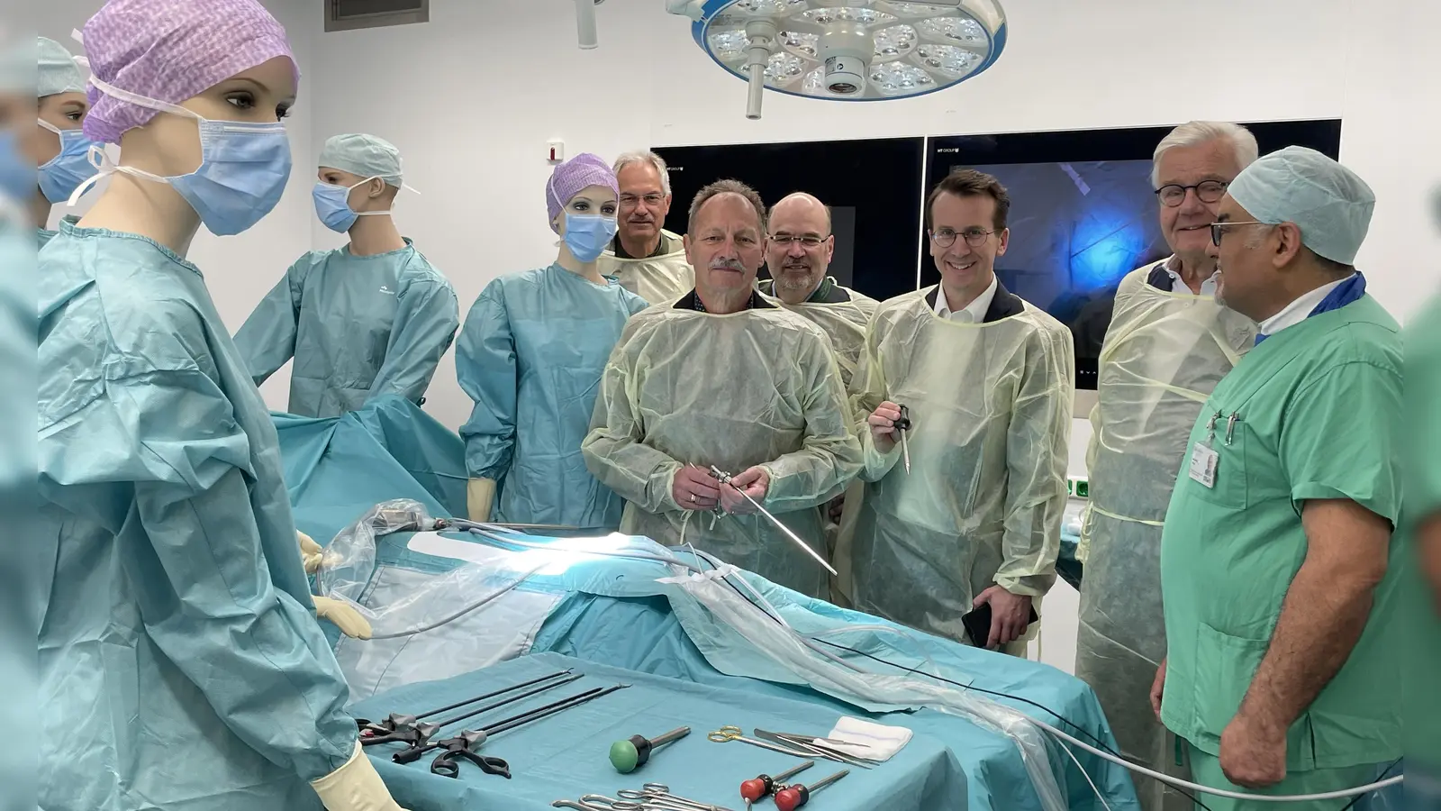 Ehrengäste, Ärzte und als OP-Schwestern verkleidete Schaufensterpuppen stehen am OP-Tisch im neuen Saal.  (Foto: pst)