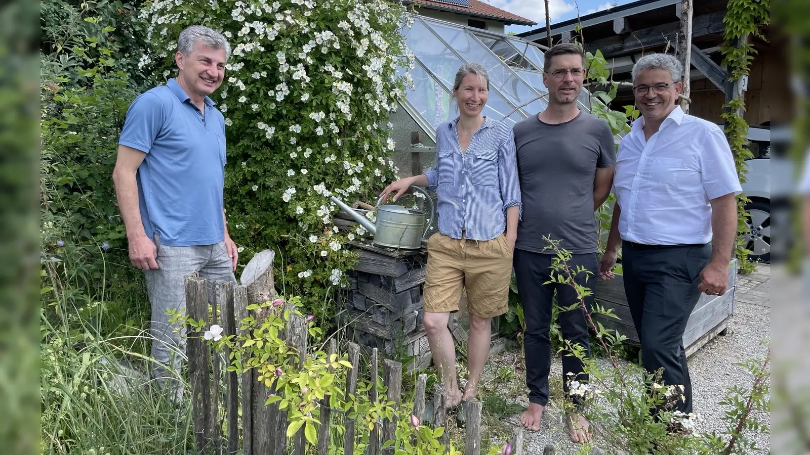 Jürgen Ehrhardt (v.li.) und Stellvertretender Landrat Matthias Vilsmayer (re.) stehen vor dem üppig blühenden Wildrosenstrauch von Christine und Nikolaus Rathert in Hechendorf. (Foto: pst)
