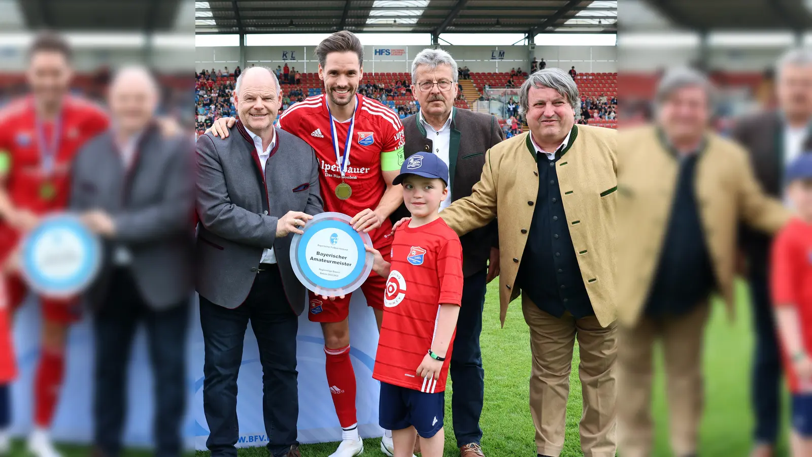 Der sieben Jahre alte Luca erhielt von BFV-Schatzmeister Jürgen Faltenbacher (4.v.l.) und Spielleiter Josef Janker (2.v.r.) den Glasteller des „Bayerischen Amateurmeisters” für die SpVgg Unterhaching mit Markus Schwabl (2.v.l.) und Seppi Welzmüller (3.v.r.). (Foto: Fabian Frühwirth/BFV)