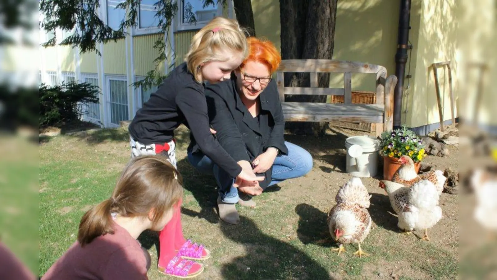 Die vier Hühner sind das Aushängeschild von „Wunderkind”, sehr zur Freude der Anwohner und Passanten. „Wir werden häufig auf die Hühner angesprochen. Die Leute nehmen da großen Anteil.“ Deborah Neuburger hilft beim „Fütterdienst“. (Foto: US)