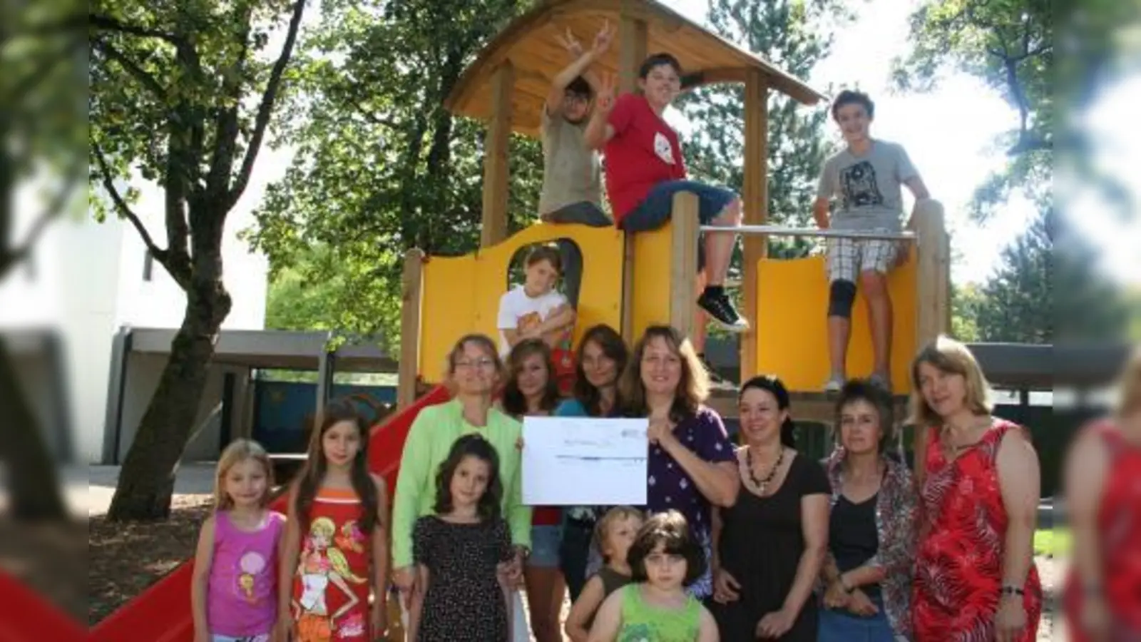 Kinder und Erzieher des Horts „Namen Jesu” freuen sich über die Spende des „Mütterforums”. Alexandra Gaßmann überreichte Kindergartenleiterin Maria Frank-Maana (links) einen symbolischen Scheck. (Foto: tg)