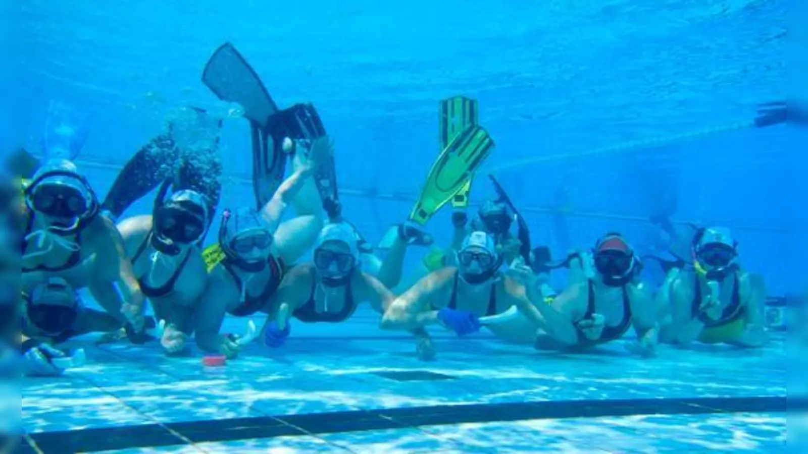 Die Münchner Unterwasserhockey-Spielerinnen mit ihrem Sportgerät, dem Stick, und Bleipuck (rot).	 (Foto: Verein)