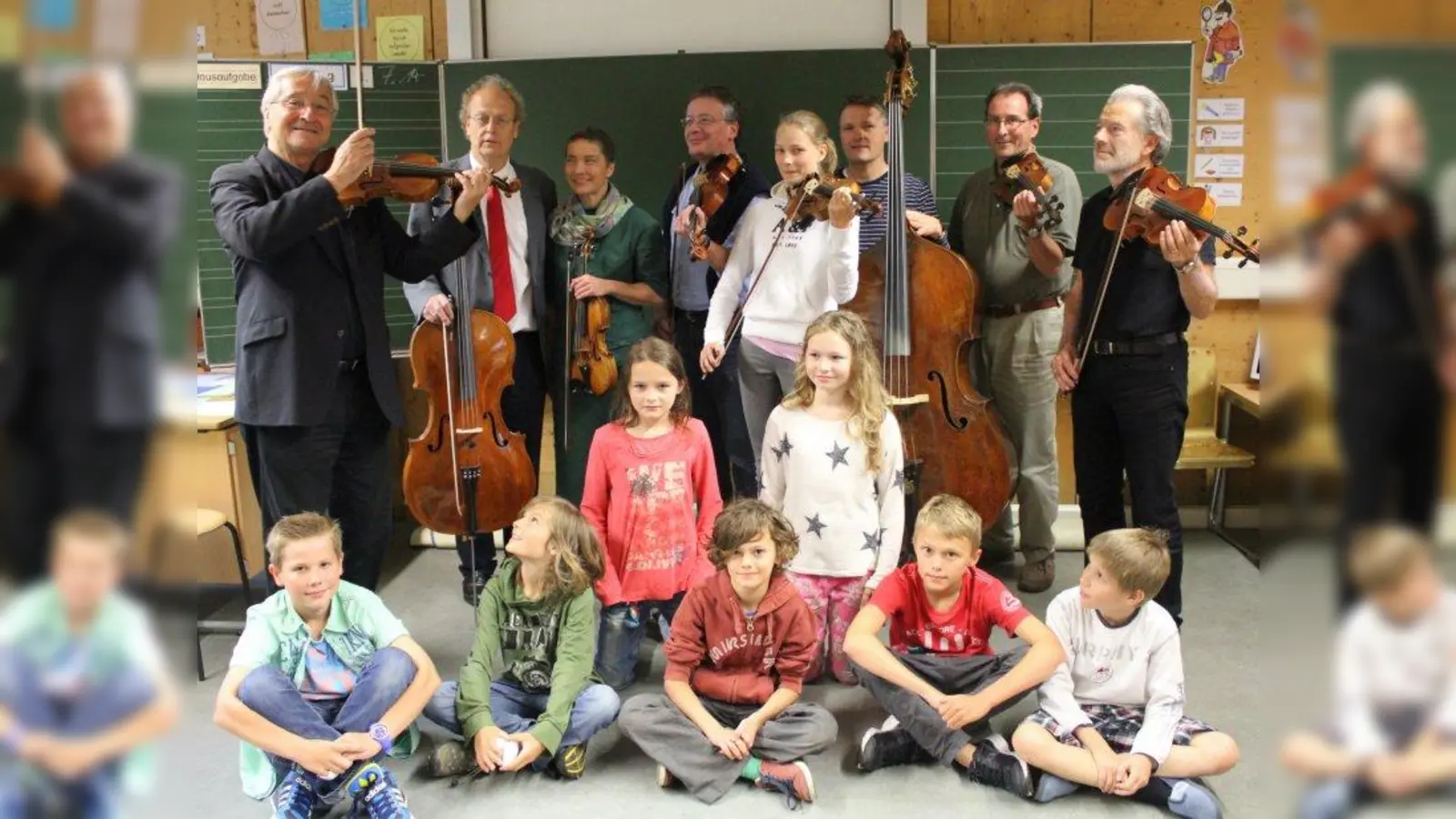 Kinder der 4c mit einigen „ihrer” Musiker vom Orchester „Zarge”. Links Dirigent und Orchesterleiter Bernhard Tluck, rechts Grundschulrektor und Gründer der „Zarge” Christian Marek. (Foto: US)