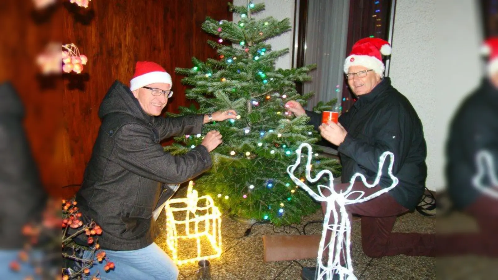Georg Ringmayr (l.) befestigt die letzten Lichter am Christbaum. (Foto: pst)
