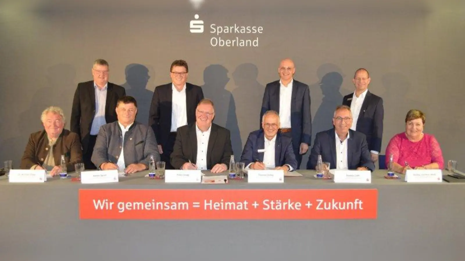 Michael Rapp, Anton Speer, Peter Lingg, Thomas Orbig, Markus Loth, Andrea Jochner-Weiß (sitzend von links), Martin Maurer, Michael Müller, Markus Lang und Michael Lautenbacher (stehend von links) freuen sich über die nunmehr besiegelte Fusion der Sparkasse Oberland mit der Kreissparkasse Garmisch-Partenkirchen. (Foto: mka)