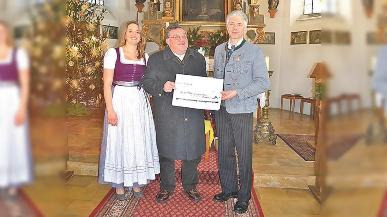 Volksmusikwart Magdalena Schulz, Pfarrer Toni Wolf und Vorstand des Trachtenvereins Georg Hauser bei der Spendenübergabe in der St. Nikolaus Kirche in Brunnthal. (Foto: VA)