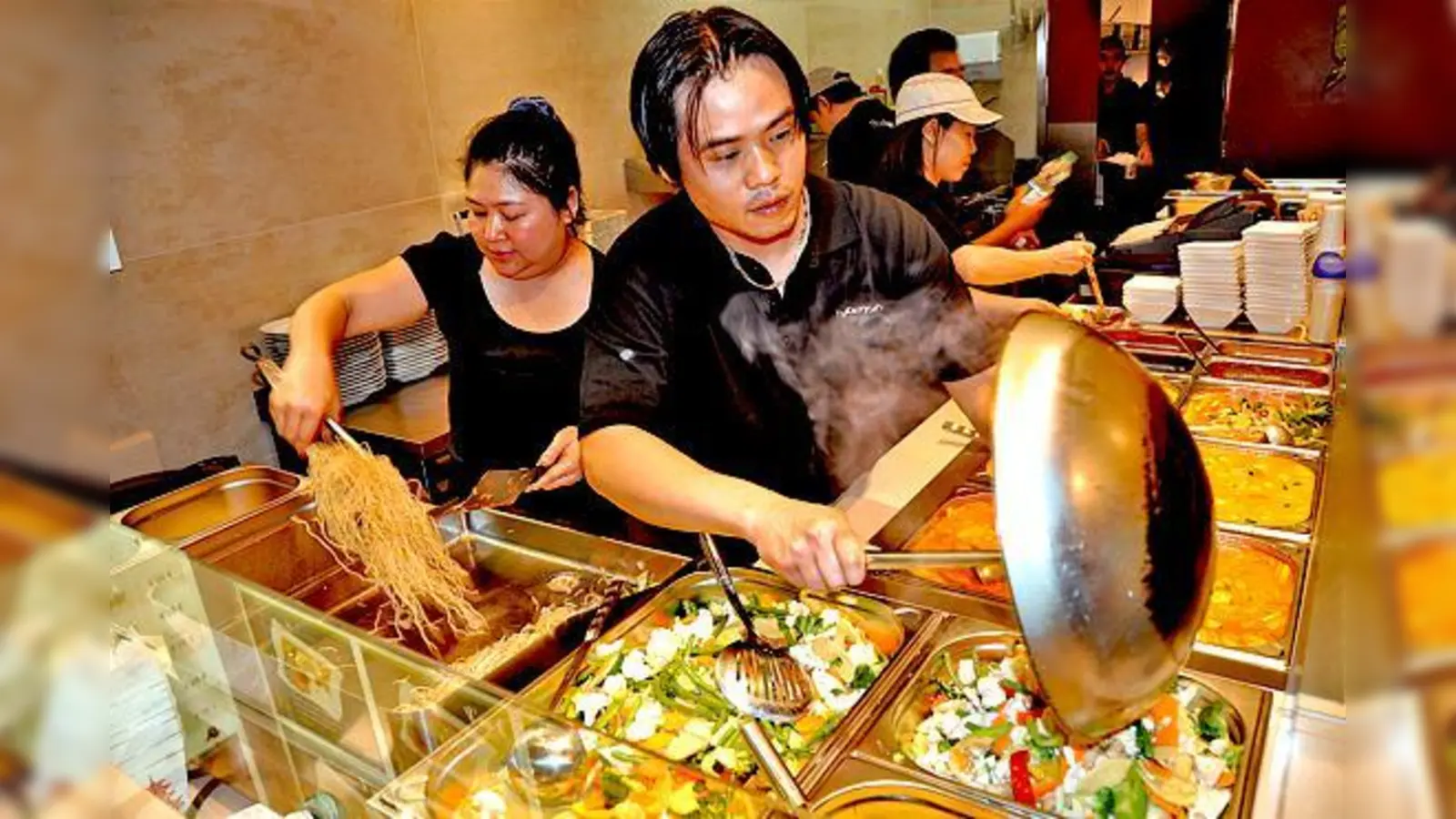 Immer frisch  (Foto: Pham Thi Dien Thuy (links) füllt zusammen mit einem Mitarbeiter frische Zutaten in die heißen Pfannen.)