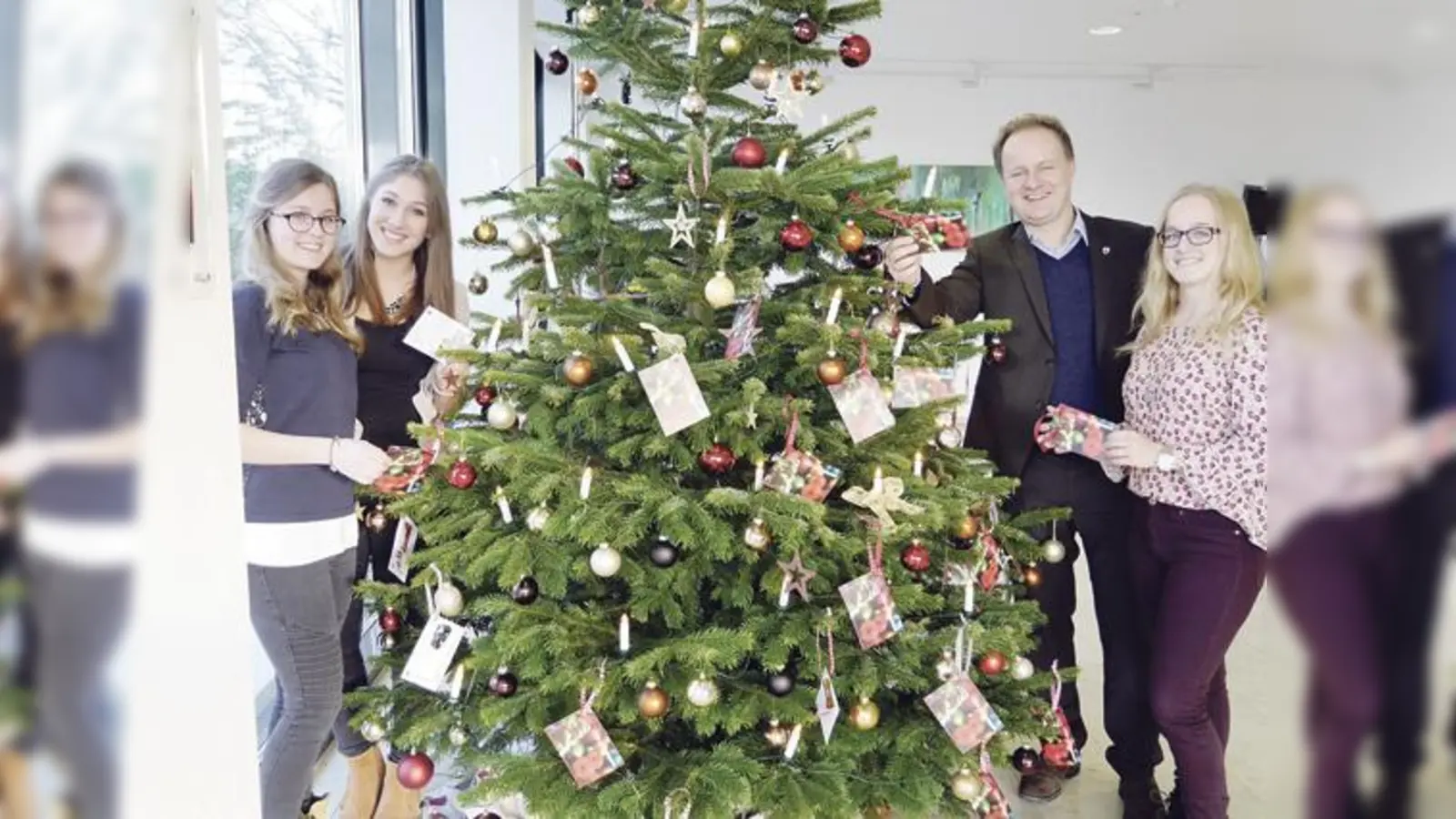 Die Auszubildenden Melanie Adam, Sophia Bartl und Katharina Budenhofer (von links) haben den Wunschbaum geschmückt. Landrat Robert Niedergesäß ist mit dem Ergebnis zufrieden und freut sich auf die Bescherungsfeier. 	 (Foto: LRA)