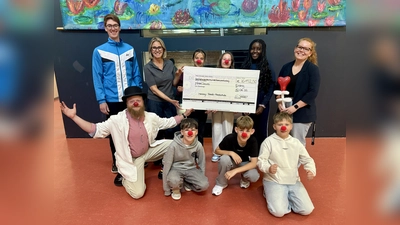 Fabian Lautner (Organisator Spendenlauf, li.), Anja Schwaneberg-Jinks (2. Konrektorin, 2.v.li.), Alina Boenke (Organisatorin Spendenlauf, re.) sowie Klassensprecher der 5. Klassen und KlinikClown „Muck” bei der Spendenübergabe. (Foto: Bettina Fiehl)