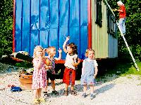 Anna, Niklas, Vicente und Paula machen Faxen, während Annas Papa Uli Horst am Bauwagen werkelt. Denn die »Schutzhütte« muss bis zum Start des Naturkindergartens im September fertig sein.