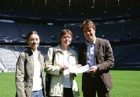 Ilona Kraus und Tochter Ramona nehmen die beiden Tickets von Alexander Pieper (Geschäftsleitung Marketing bei Arena One) im Mittelkreis des Spielfeldes in der Allianz Arena entgegen.	 Foto: cr