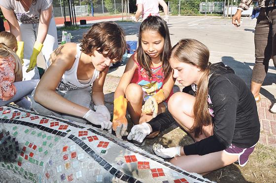 Silvia Gonzalez von Green City e.V. zeigt den Kindern, wie die Mosaiksteine gesetzt werden. Foto: Föll