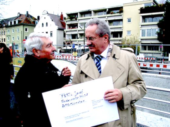 Josef Fertl übergibt Oberbürgermeister Christian Ude ein übergroßes Exemplar einer Postkarte. Es geht um den Erhalt der Bushaltestellen in Moosach. 	VA