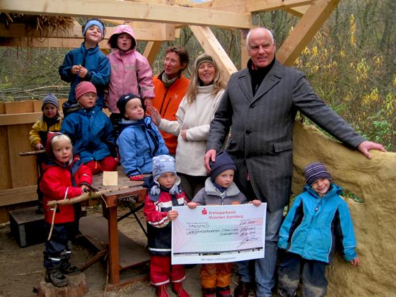 Der Vorsitzende von »Grünwald hilft«, Klaus Heun, übergab einen Spendenscheck in Höhe von 1.000 Euro an den Waldkindergarten.	Foto: VA