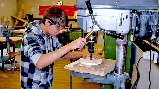 Ein Schüler der Technikgruppe beim Schreinern einer Holz-Etagere. 	Foto: VA