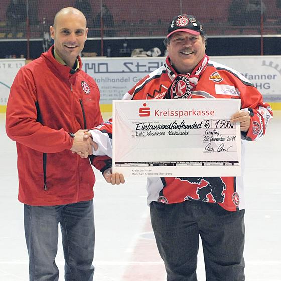 Fanklub-Vorstand Armin Fichter (l.) übergibt den Scheck zur Unterstützung der Nachwuchsarbeit an Uli Mezger, den zweiten Vorsitzenden des Fördervereins Eishockeynachwuchs Grafing. Foto: ehc/smg