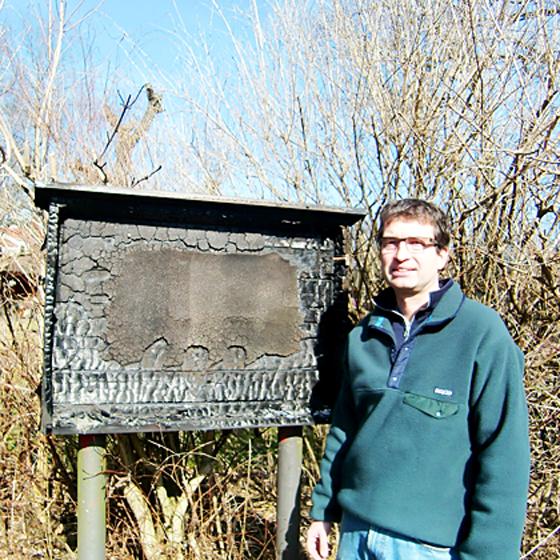 Johannes König, Vorsitzender des Kleingartenvereins Schlösselgarten im  Cosimapark, vor den verkohlten Resten eines Schaukastens. Foto: ikb